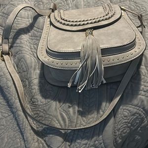 Small gray saddle crossbody bag with tassel.  This hands free back is cute.